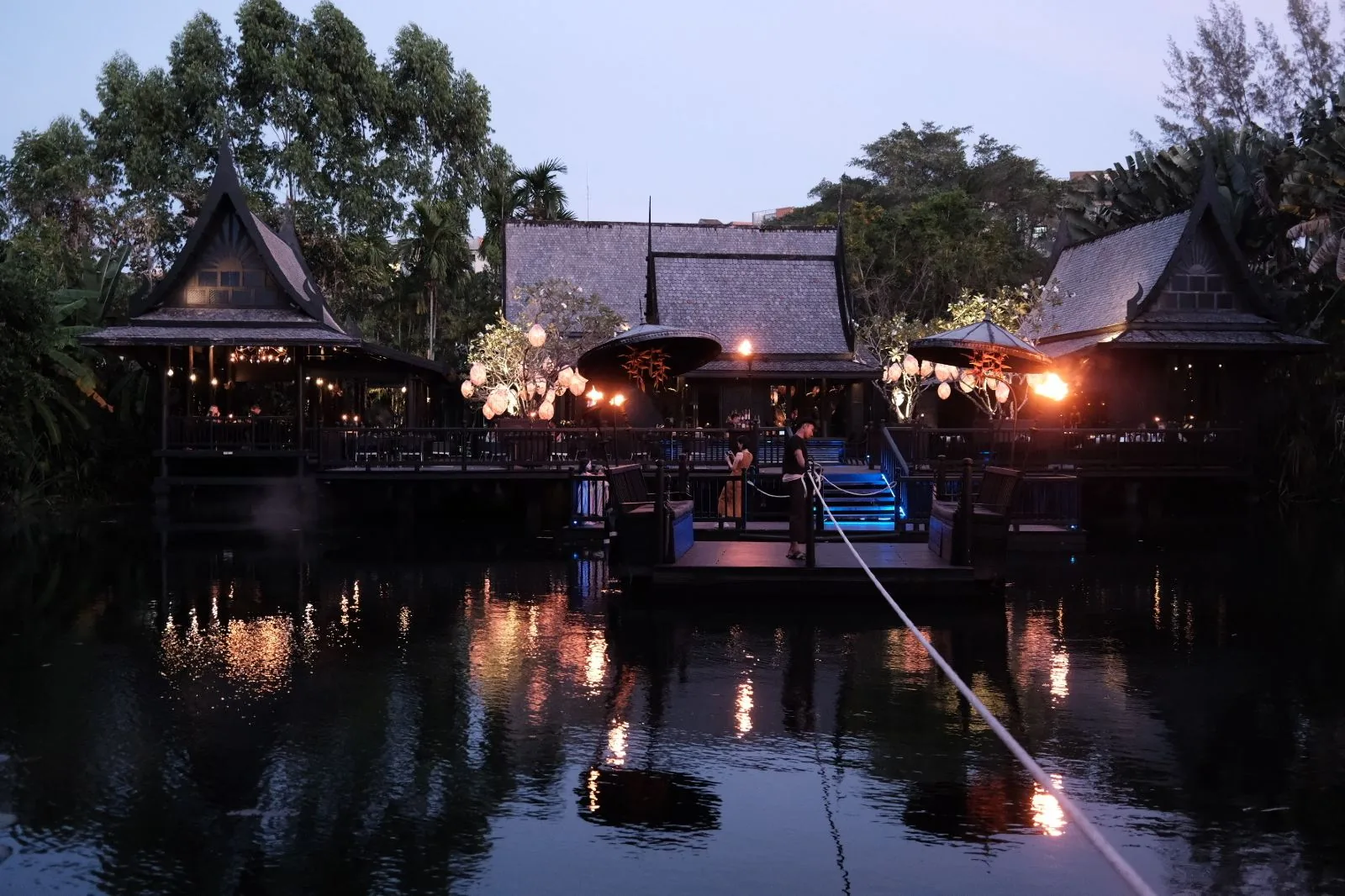 Black Ginger — traditional Thai houses lit over the lagoon at night